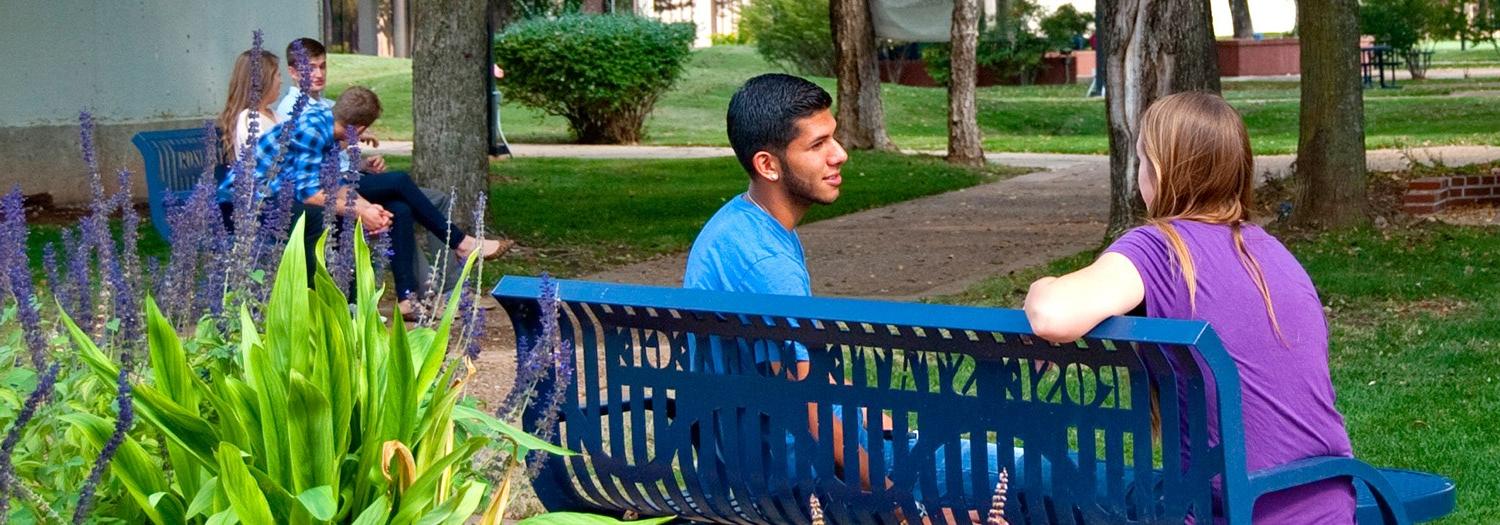 Students seated on a bench in the mall area.